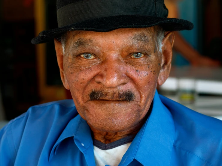 an old man wearing a hat and a blue shirt