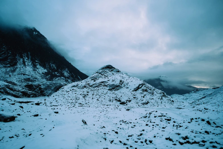 a large snowy mountain side under a cloudy sky