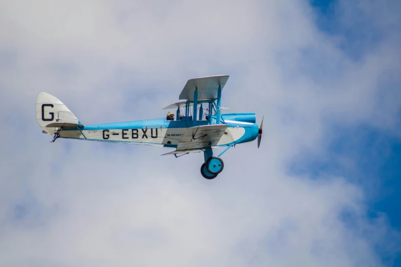 the plane is flying through the blue cloudy sky