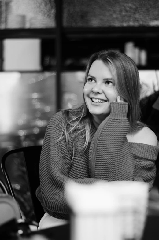 a black and white po of a smiling woman sitting at a table