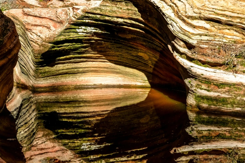 the reflection in a pool of water near rock formations