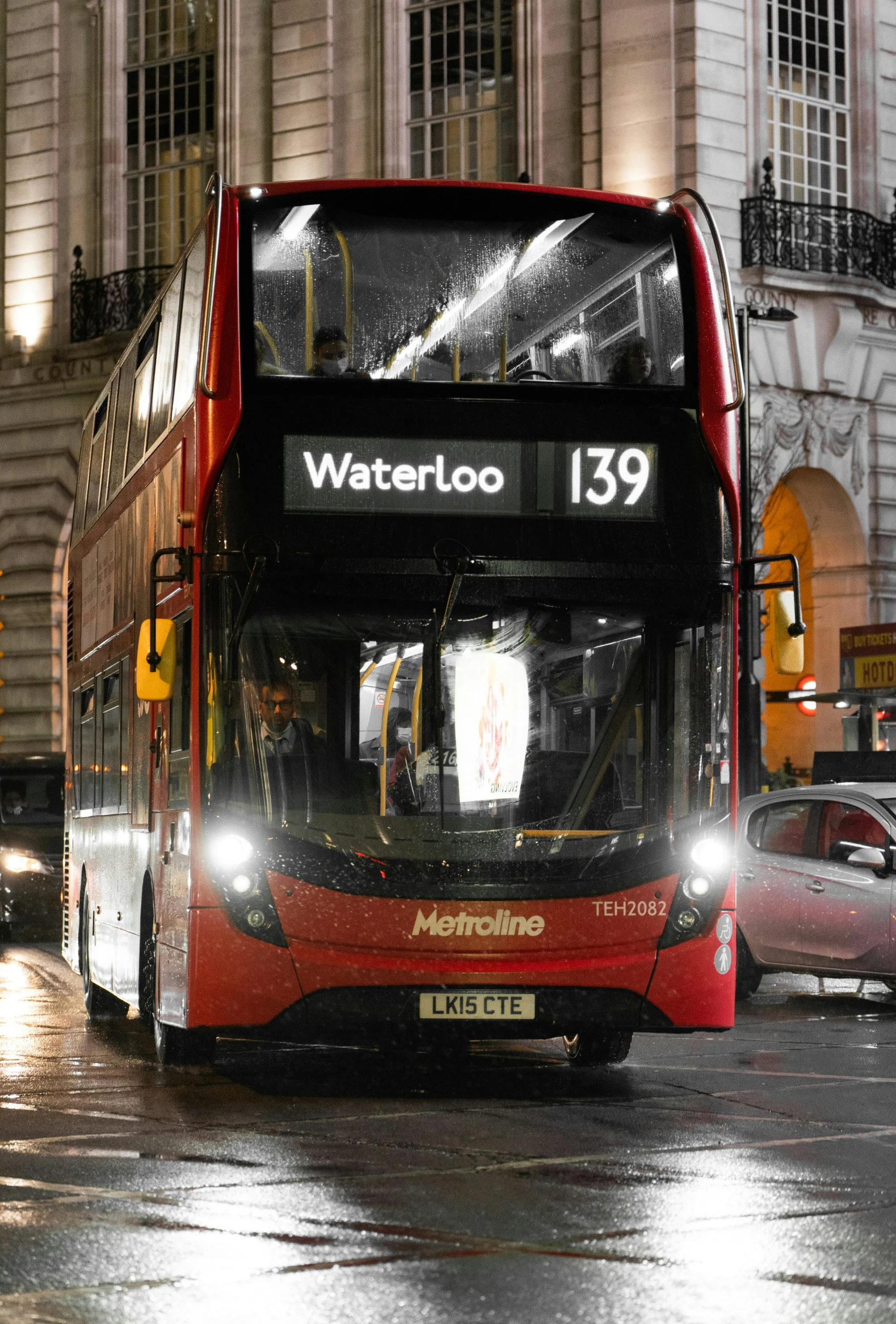 a city bus driving in the rain at night