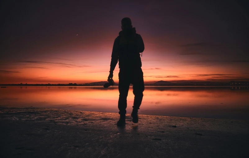 a man standing on the beach looking at a sunset