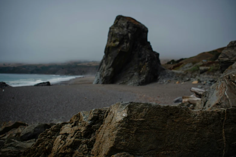 some rocks are standing near the beach on a cloudy day