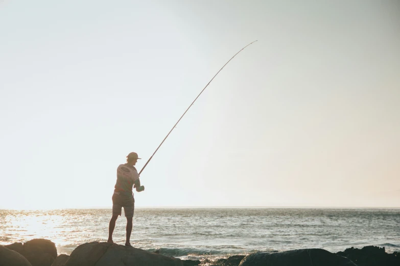 the man is fishing on the beach in the water