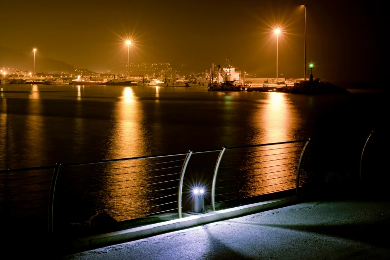 a dark harbor with street lights reflected on the water