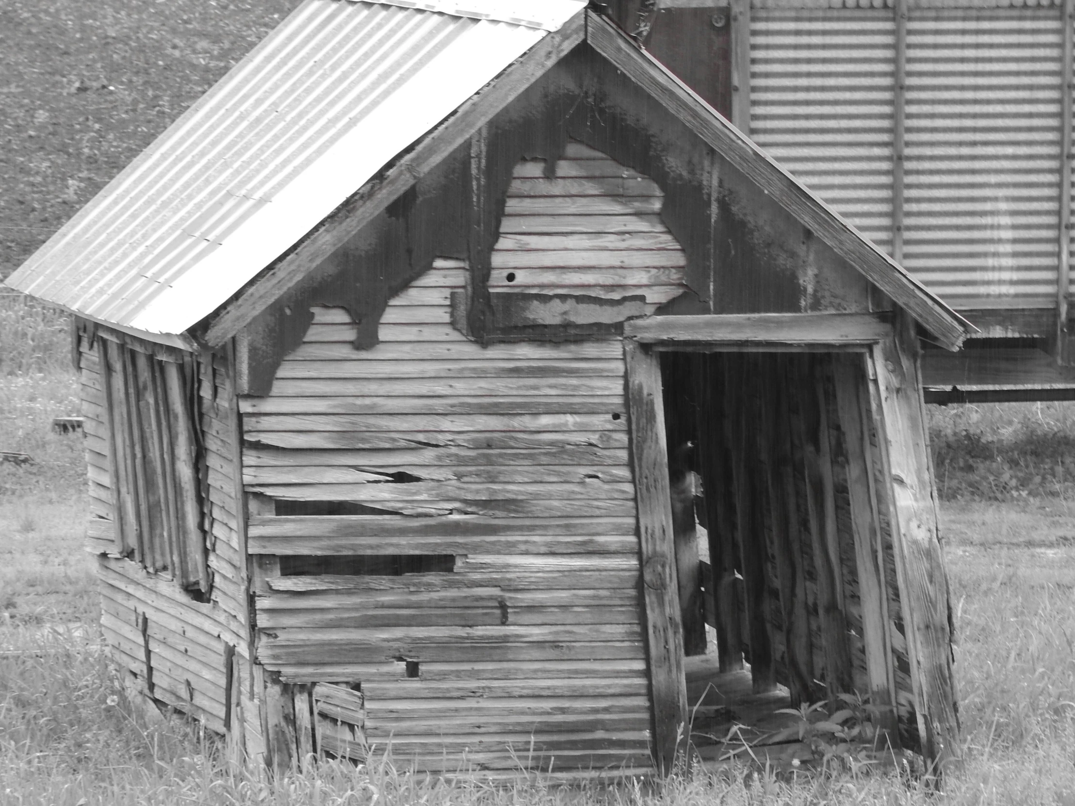 an old building in an open field with a metal roof