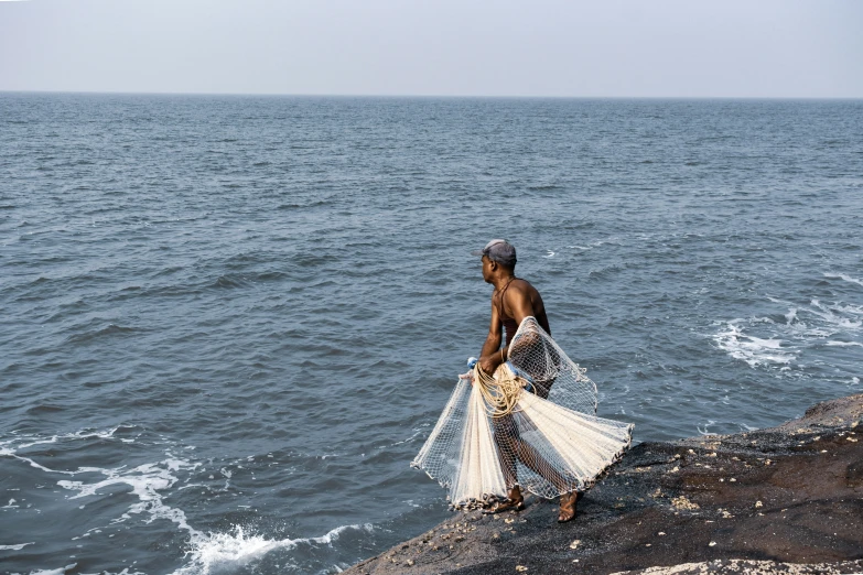 a woman is walking along the edge of the water with her net