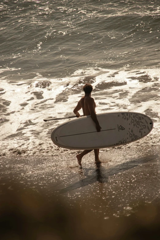 surfer carrying surfboard on low waves at the beach