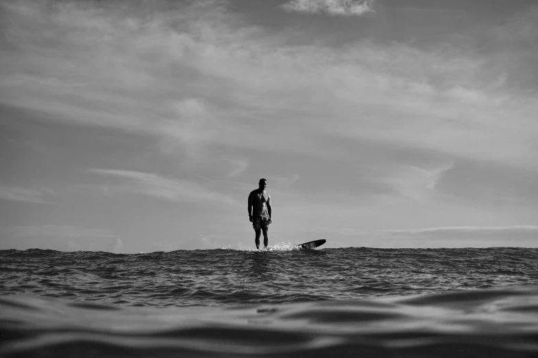 a man stands in the ocean while holding his surf board