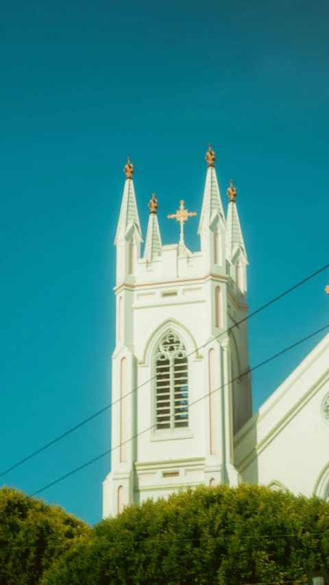 an old, white church building with steeple crosses sits against the blue sky