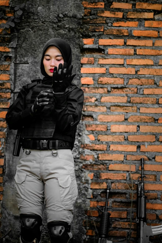 an asian woman stands with her hand on the face while wearing goggles and holding guns