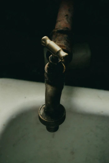 a rusty, worn up faucet sitting on a marble pedestal