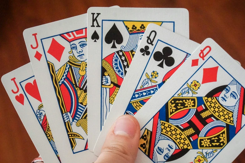 a hand holding four card playing cards next to each other