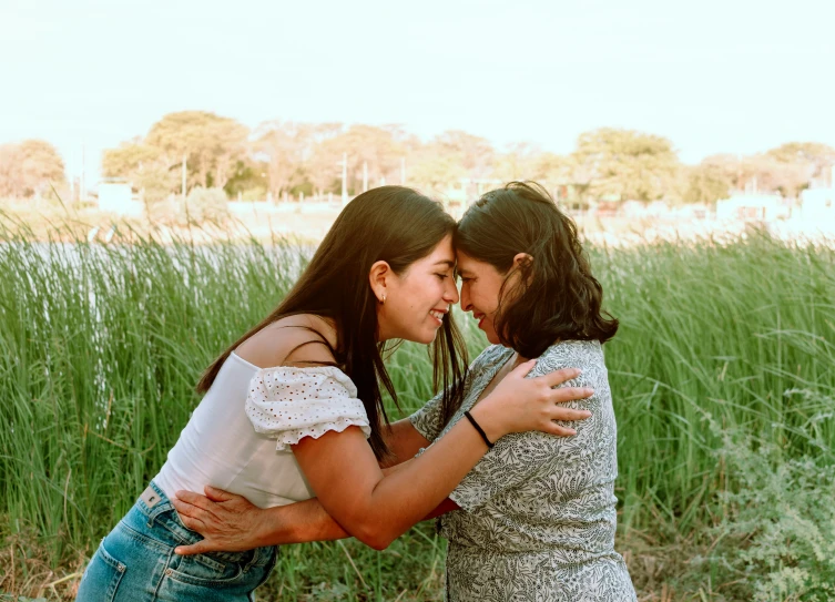 two girls emcing and looking at each other in tall grass