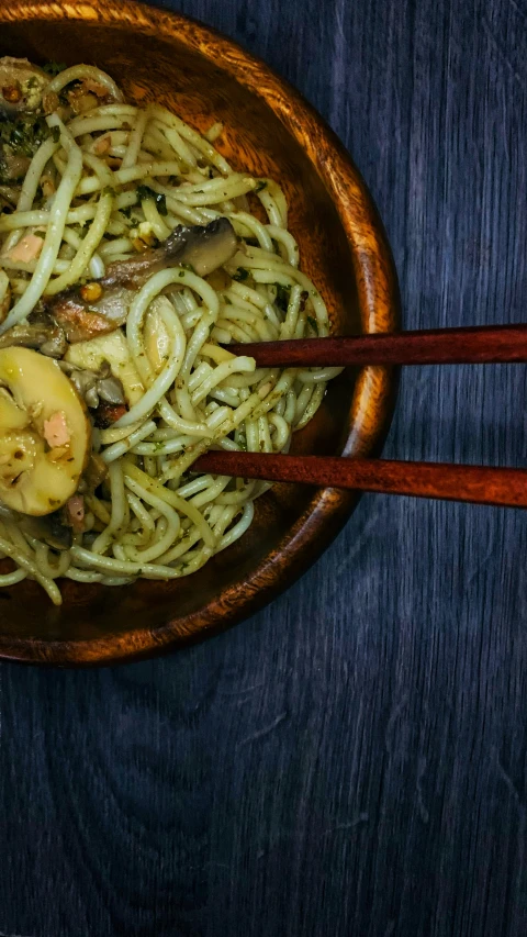 a wooden bowl full of pasta and vegetable stir fry