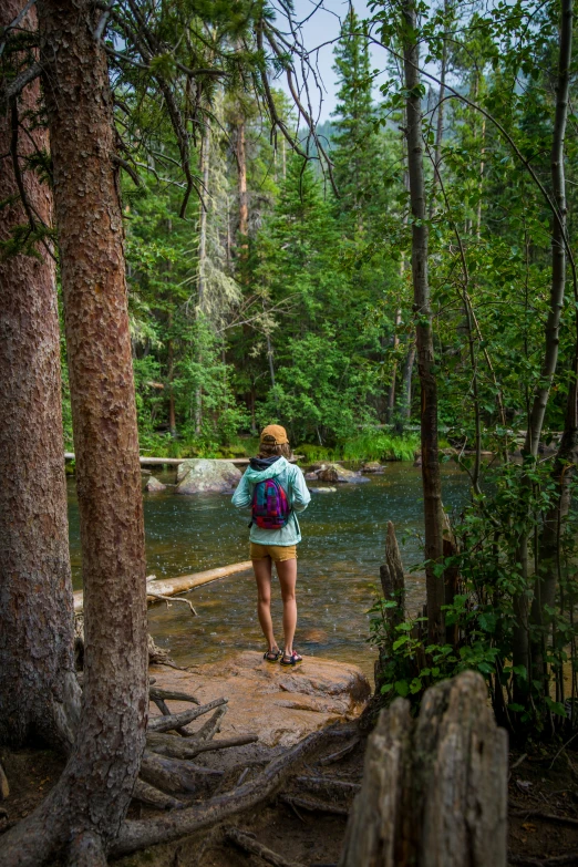 a woman standing by a creek in a forest