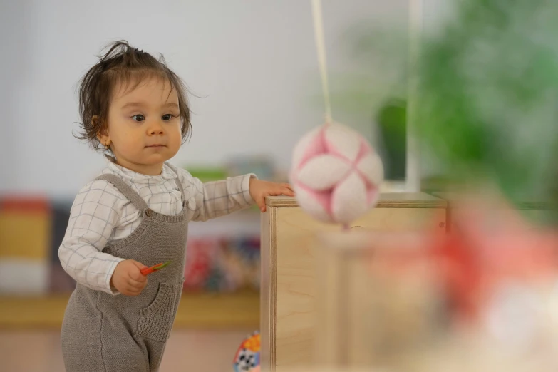 a baby girl is standing in front of a wooden box