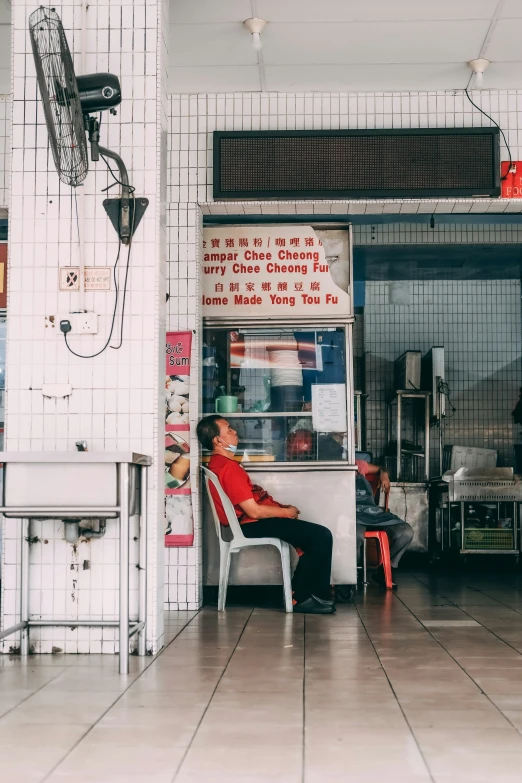 a man sitting in a chair while ordering at an outdoor restaurant