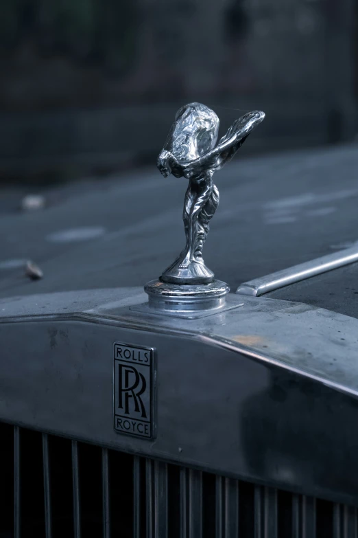 a silver car badge featuring a statuette of a child holding a baseball bat