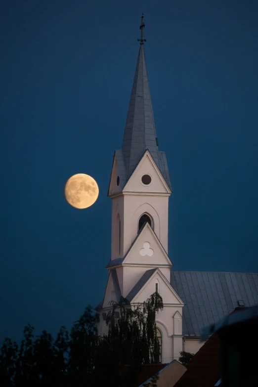 the moon sets behind an old church building in a city