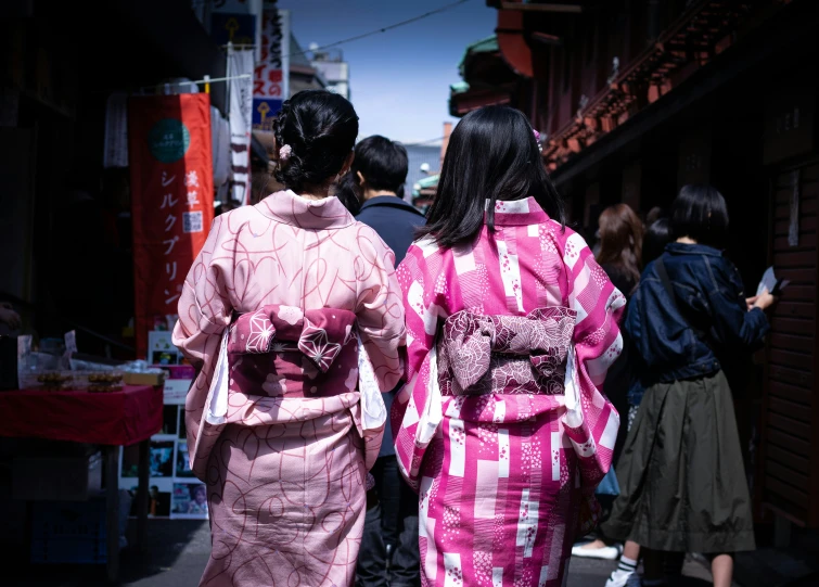 a pair of asian ladies are walking down a street