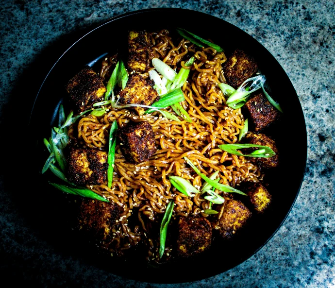 a plate topped with meat and noodles covered in sauce