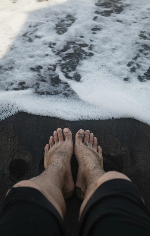 a person standing on top of the ocean next to a foamy beach