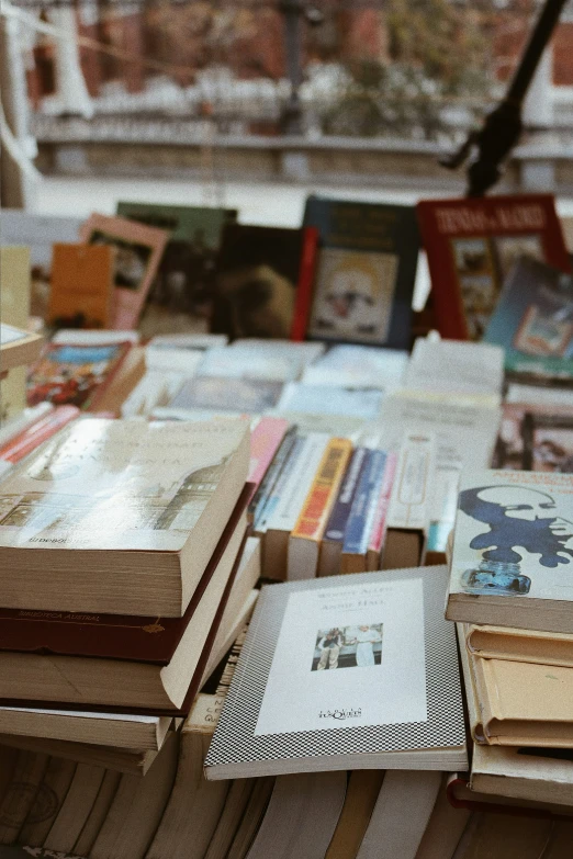 many books are stacked on a table, in a bookstore