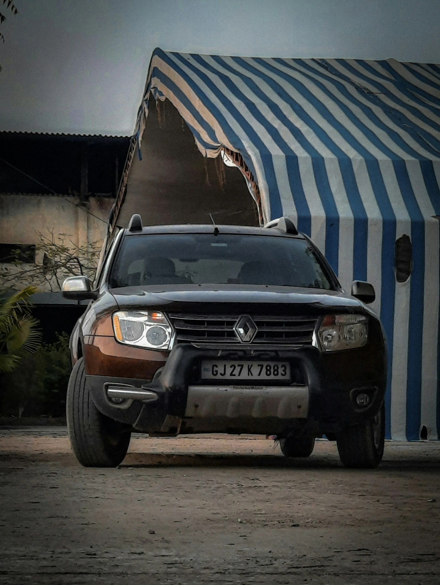 a very big black car parked by some tents