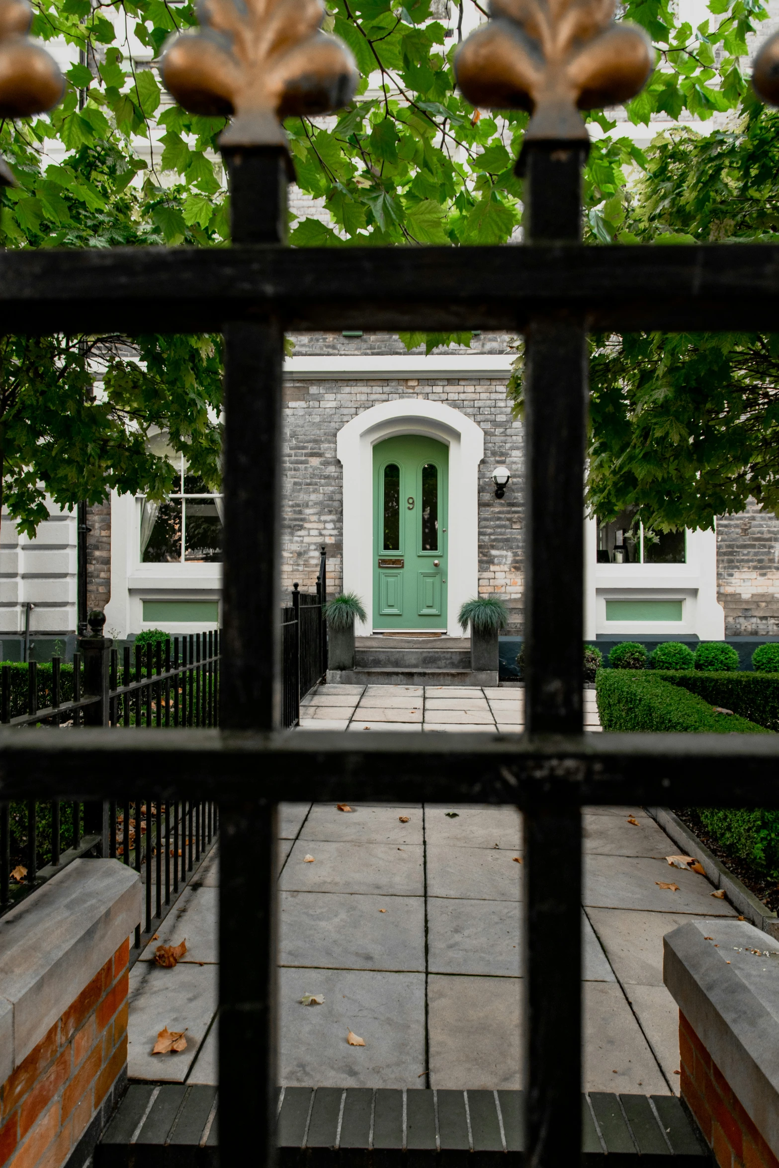 the front entrance of an older mansion viewed through a wrought iron fence