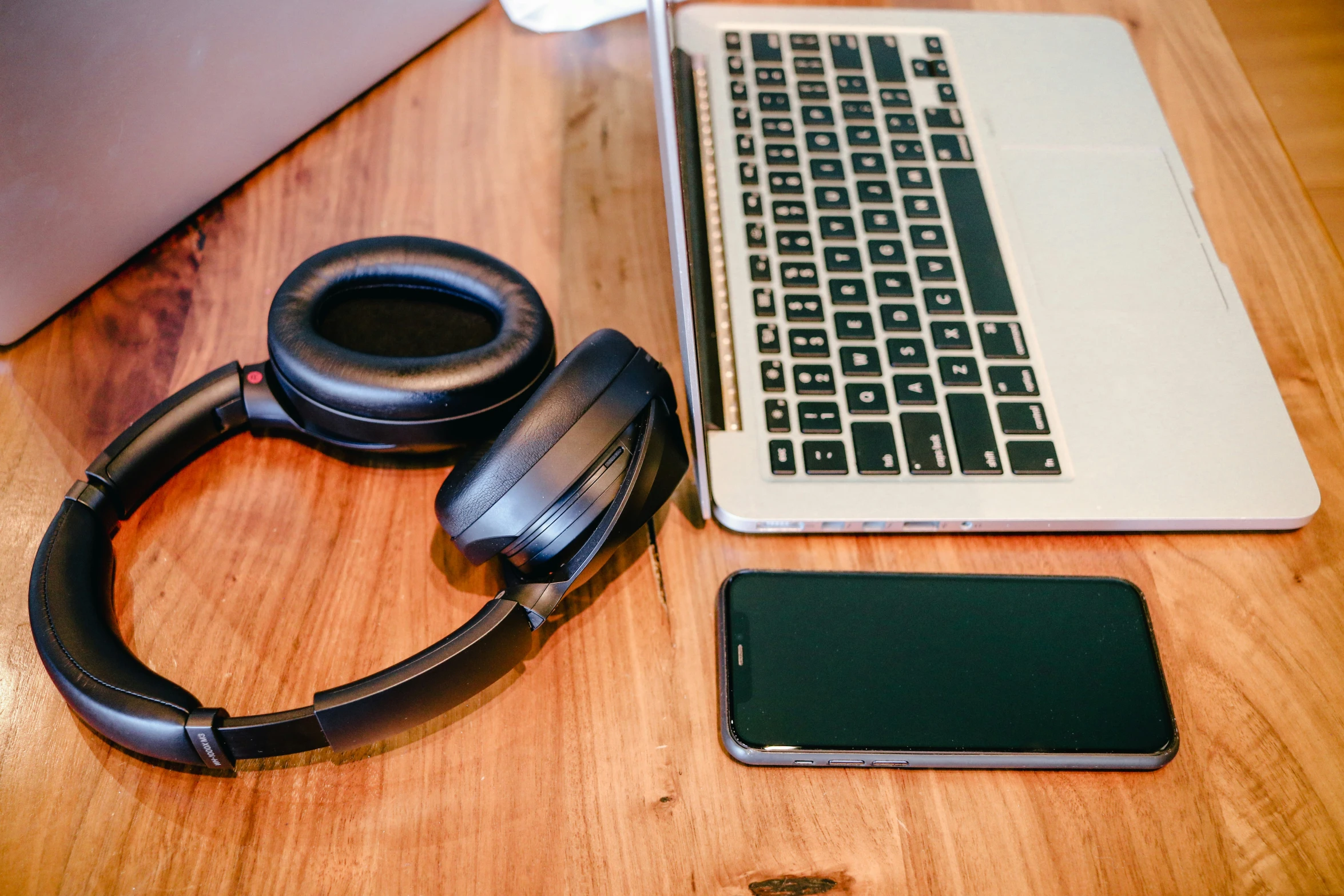 an iphone and headphones next to a laptop on the desk