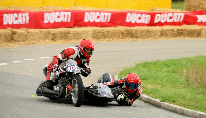 a couple of men riding motorcycles around a corner