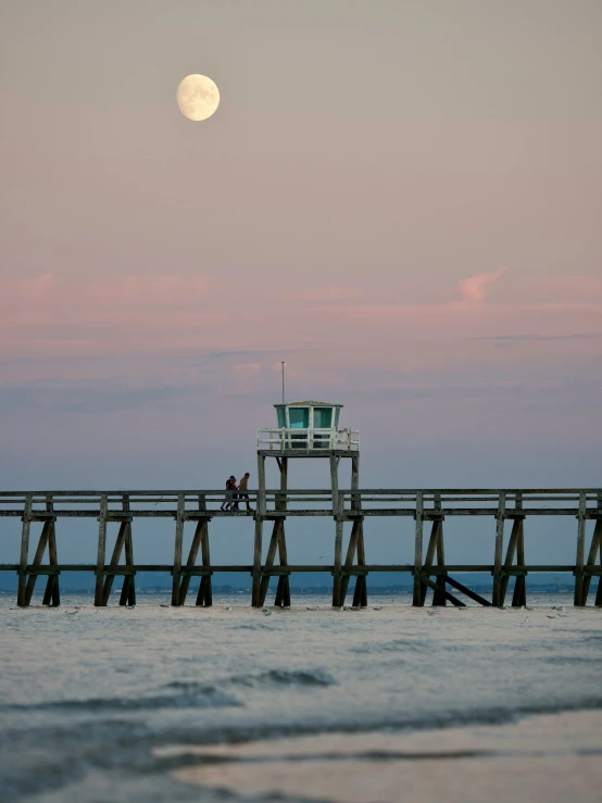 a pier with a full moon over water