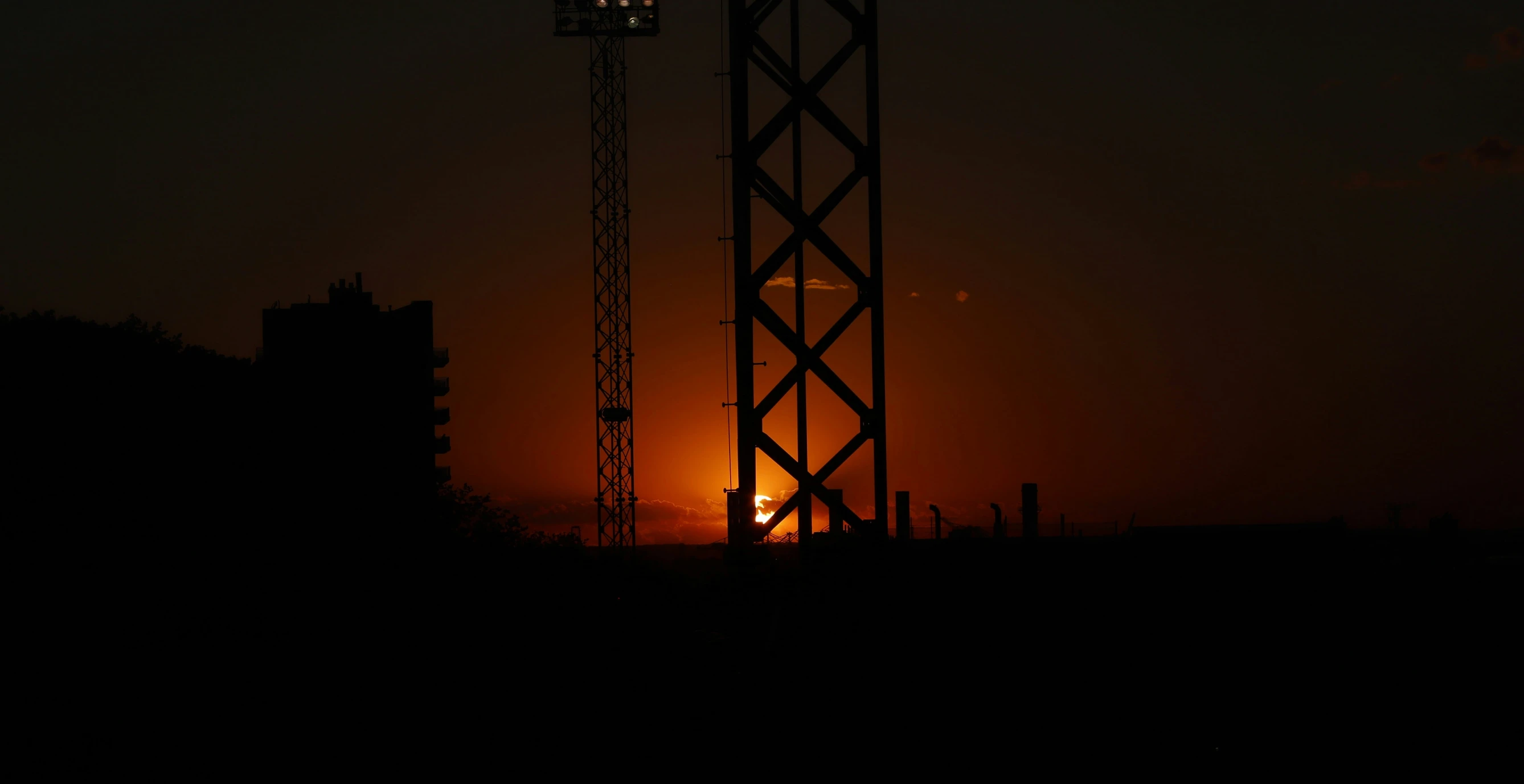 the sun setting behind a tall tower with a clock