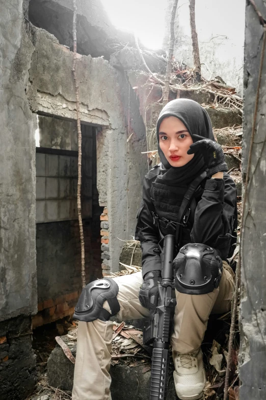 a female soldier kneeling near an abandoned building