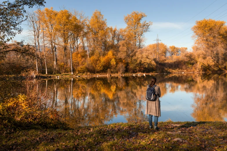 a man standing on a field in front of a lake