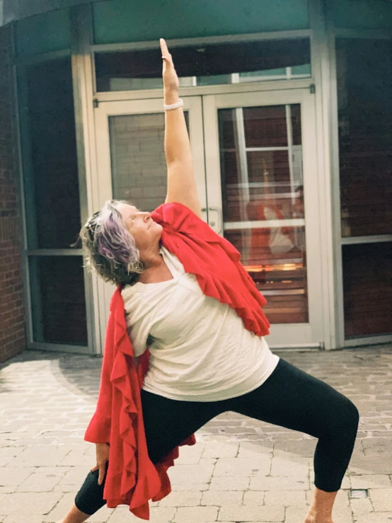 a woman in black pants and a red scarf performs a yoga pose