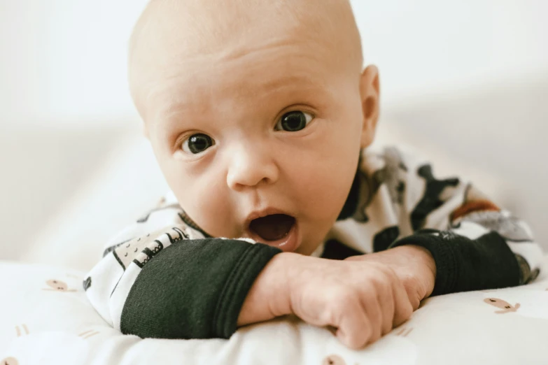 a baby sticks his hands out while laying on his back