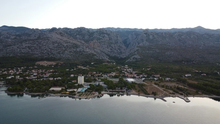 a bird's - eye view of a town nestled on the shore of a lake surrounded by mountains