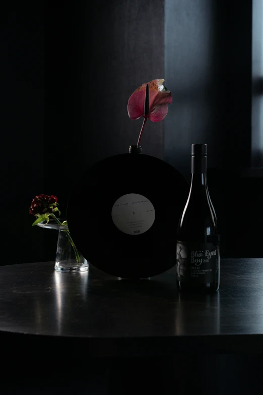 there is a vase on a table with wine and flowers