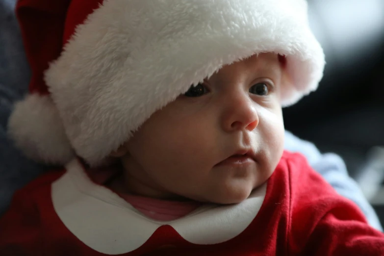 a close up of a baby wearing a santa clause hat