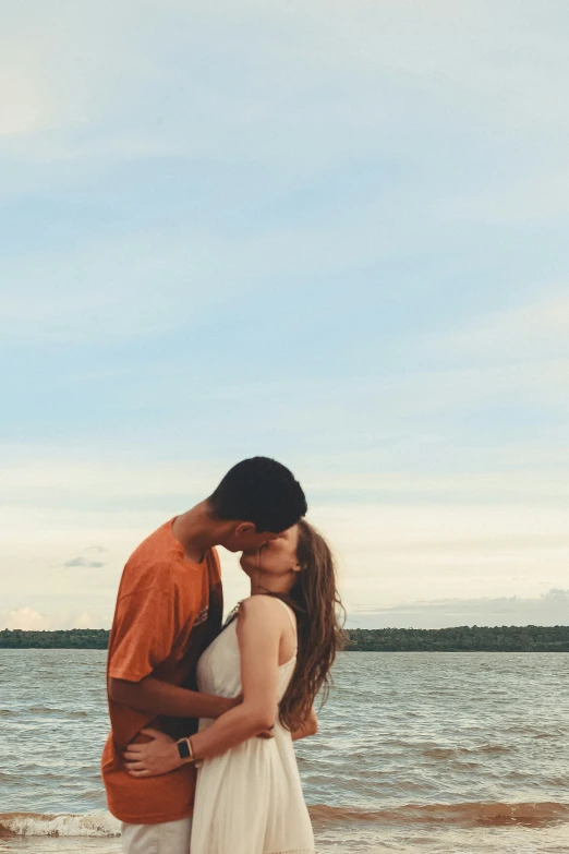 a man and woman kissing on a beach