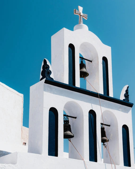 white building with bells and bell tower with cross on top