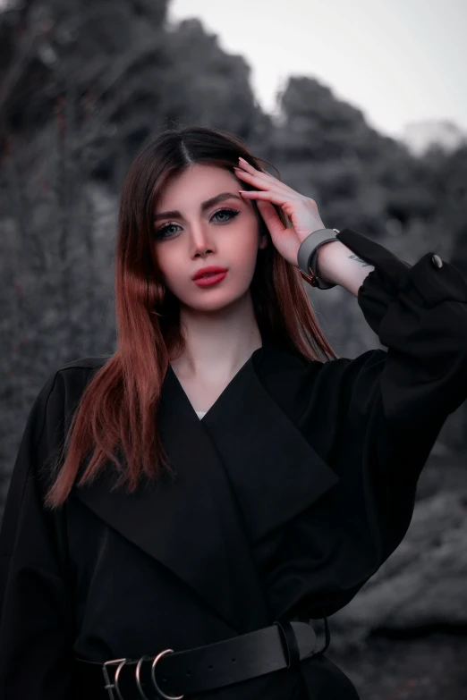 young woman wearing black dress holding her hair in low wind