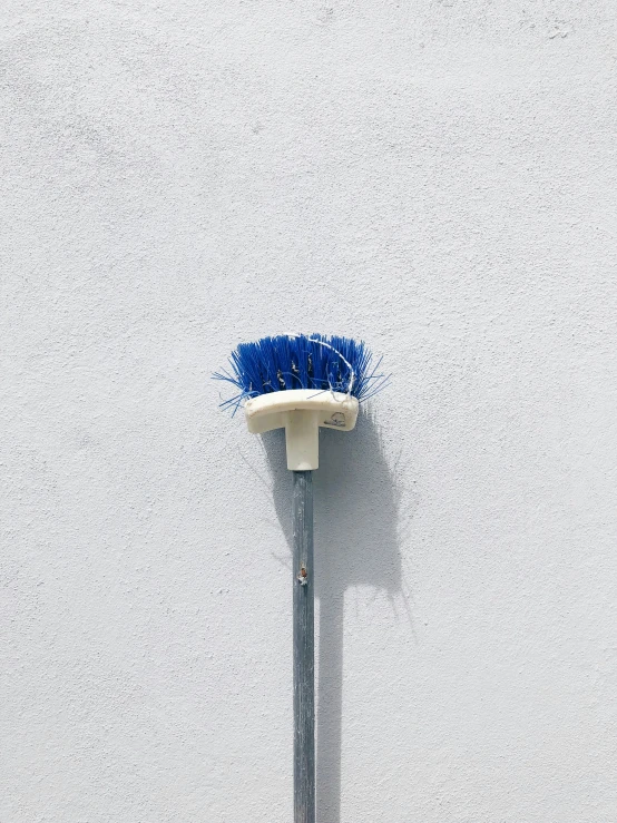 a blue brush leaning up against the wall