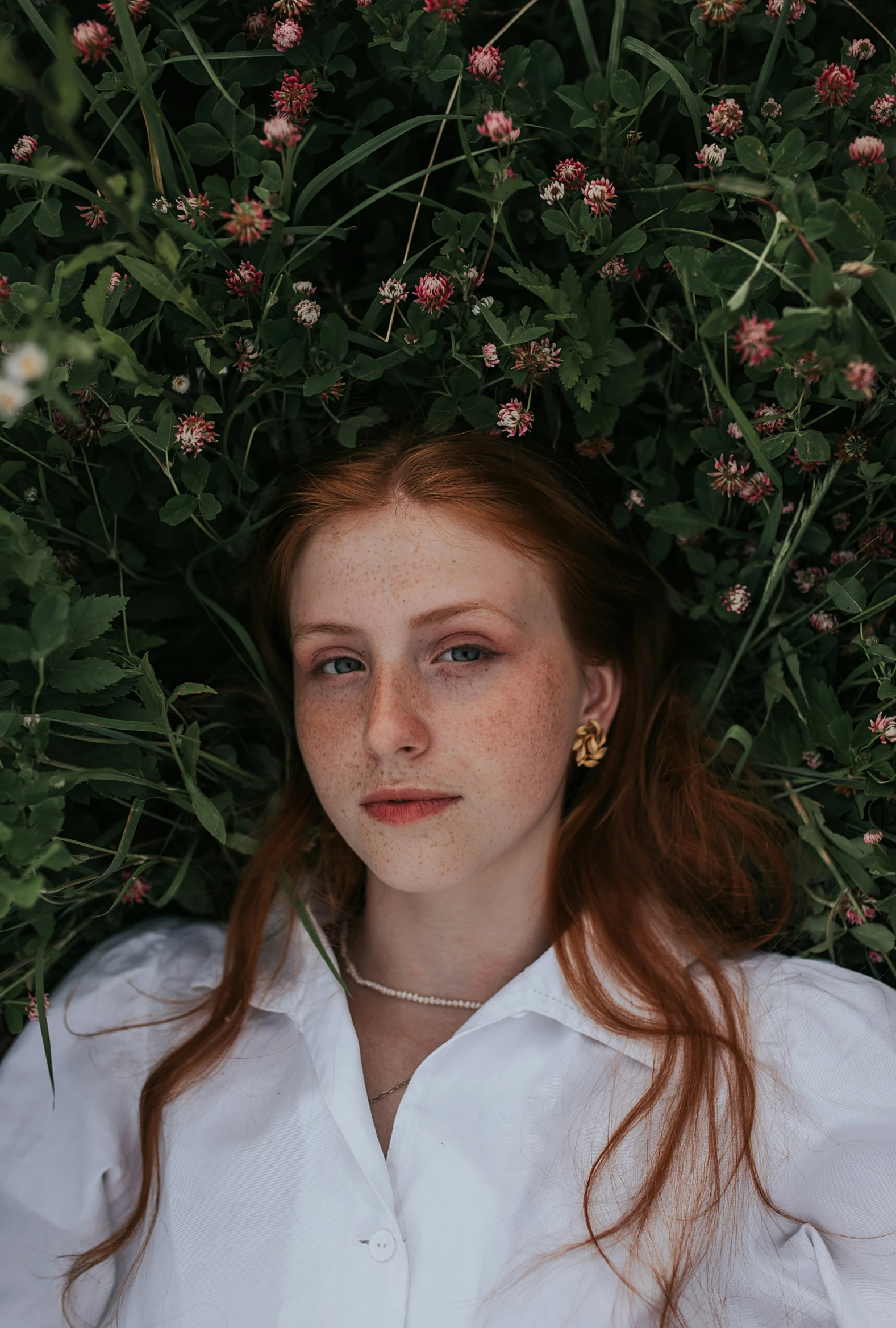 a woman in white shirt laying next to plants