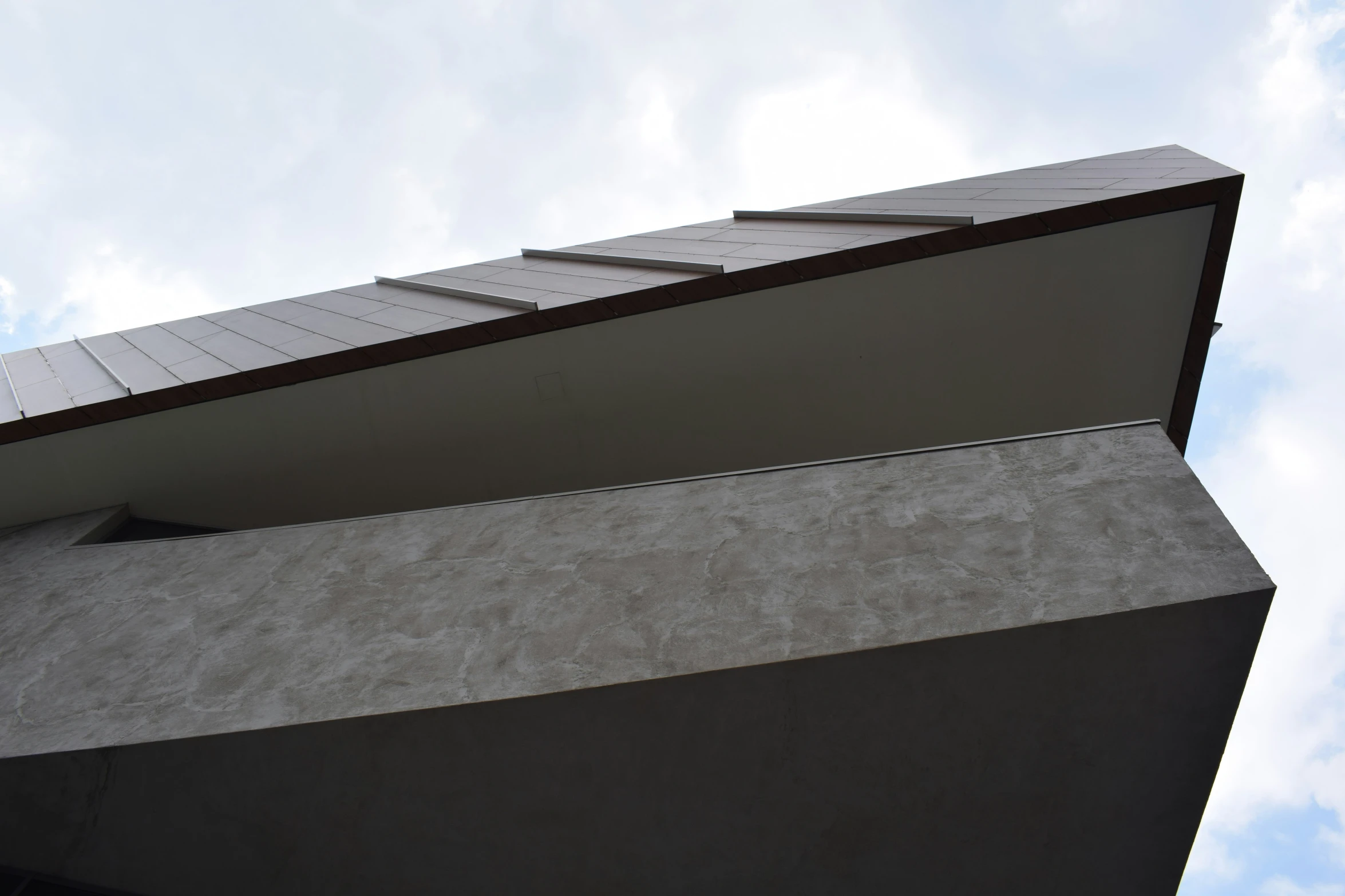 the corner of the side of a building against a blue cloudy sky