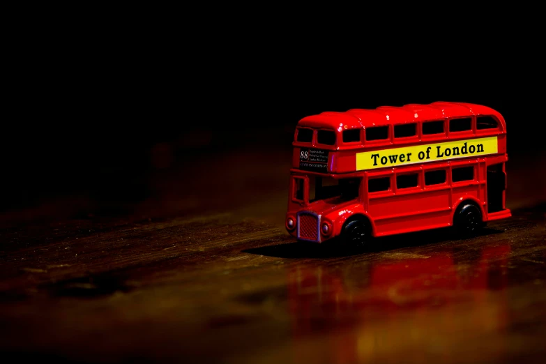 the toy bus is red and has yellow decals on the side