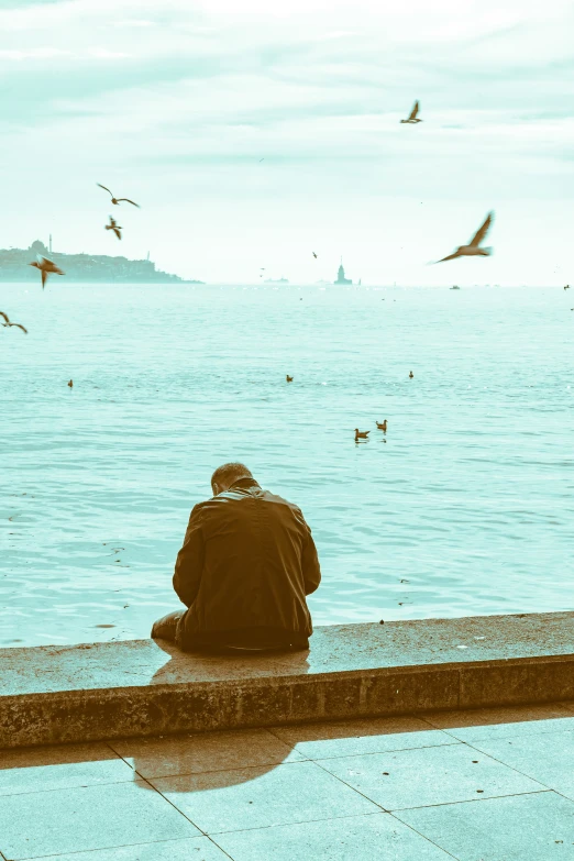 the man is sitting in the shade by the water